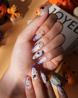 Witching Hour press on nails with a black spider web, bats, ghost, black cat and jack-o'-lanterns on a nude base with purple glitter edges - image 3
