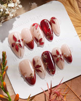 Crimson Petals press-on nails with deep red French tips, nude base, gold outlines and floral details