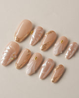 Venus hand-painted shell press-on nails with soft nude shimmer and gold accents