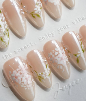 First Vow handmade press-on nails featuring Gentle Milk Tea Nude, Hand-painted White Florals & Pearl Accents.