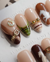 Close-up of THE HEIR press-on nails with vintage plaid, metallic horsebits and horse silhouettes