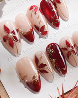 Close-up of Crimson Petals press-on nails with red French tips, gold outlines and floral details
