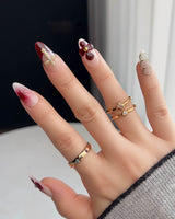 Tip Burgundy Nails with glossy burgundy tips, gold cross detail, and soft floral nail art