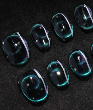 Absinthe press on nails in black with an emerald green cat eye halo and small silver star accents - image 1