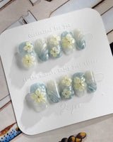 Bora Bora Blue short oval nails with luminous wave texture and sculpted tropical flowers