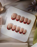 Bow French press-on nails in extra short oval shape — nude base red chrome french gold outline bow accent
