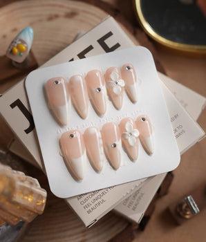 Ceramic press-on nails in medium stiletto shape — Classic Nude Pink Ombré, 3D White Florals & Minimalist Rhinestones.