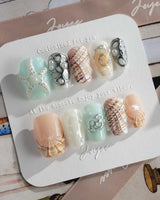 Coastline Edit hand-painted ocean nails with starry spiral and shell details