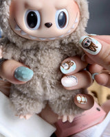 CocoaBoo Labubu short oval nails with cocoa brown, mint jelly, checker plaid, and big-eye character art