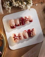 Crimson Petals press-on nails with deep crimson tips and delicate gold flower details