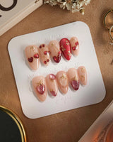 Crystal Berry press-on nails with red cherry cat-eye details, gold trim and glossy nude base