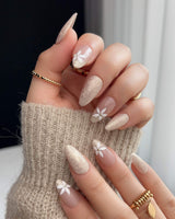 Spiral Twist press-ons with soft nude shimmer, daisy accents, and glossy gel surface