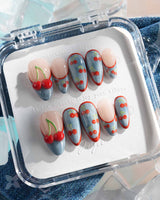 Denim Cherry medium almond nails with denim-textured tips, red French outlines, and cherry prints