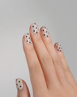 Close-up of Dot Noir-Mini nails with nude polish and black polka-dot details