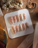 Earthy glow press-on nails with earthy nude peach color and gold foil leaf details