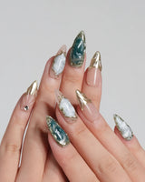 Electric Muse press-on nails with emerald green cat-eye shimmer and gold-framed nude accents