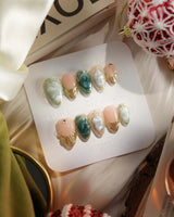 Electric Muse press-on nails with green lagoon cat-eye shimmer and raised gold frame accents