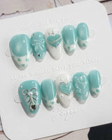 Exuma Blue extra short almond nails with light blue shine, heart accents, and ripples