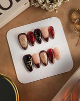 Gilded Merlot press-on nails with burgundy cat-eye French tips and gold rose accents
