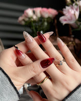 Close-up of Gilded Rouge nails with amber red gel and textured gold leaf accents