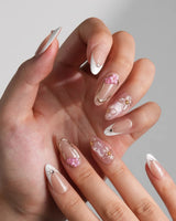 Golden Tide medium almond nails with nude French tips, metallic gold outlines, and 3D florals