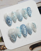 Great Barrier Blue medium almond nails with pearlescent shells, pearls, and silver chrome