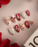 Close-up of Coquette Red press-on nails with red chrome, gold outlines, bows, roses and rhinestones