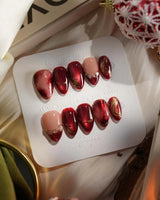 Molten Rouge press-on nails with red cat-eye gel, nude base and gold outline crystal details