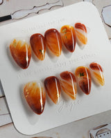 Onyx Shine press-ons with amber marble swirls, dark depth, and polished gel shine