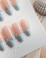 Oyster Blue medium almond nails with baby-blue French tips and pearl-lined smile detail
