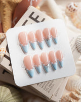 Oyster Blue medium stiletto nails with soft blue tips, pearls, and coastal chain detail