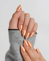 Parasol extra short almond nails with crisp orange stripes on creamy nude base