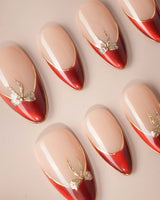 Bow French handmade press-on nails featuring nude base red chrome french gold outline bow accent