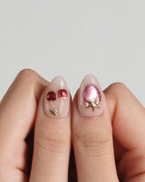 Crystal Berry press-on nails with nude base, red cat-eye cherries and dimensional gold accents