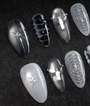 Relic press on nails in smoke grey and bone white with black marble veins, a silver starburst, a sculpted silver cross and a spiral - image 1