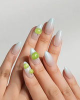 Slushie Apple short almond nails with icy blue cat-eye gradient and 3D green apple charms