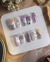 Stargaze soft birthday nails with lavender shimmer, tiny hearts, and playful cat art