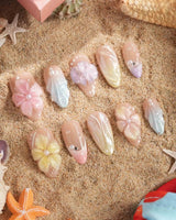Sunbathing iridescent nude pastel nails with oversized 3D florals and shell accents