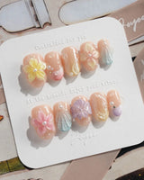Sunbathing glossy pastel nails with oversized flowers and sunlit shell accents