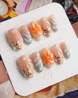 Sunset Shore short almond nails with coral nude tones, 3D flowers, and shell wave texture
