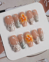 Sunset Shore medium coffin nails with nude orange base, 3D florals, and beach waves