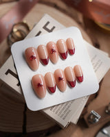 Sweet Venom press-on nails in medium almond shape — Ruby Red French, gold Outlines, 3D Red Hearts & Shimmering Lines.
