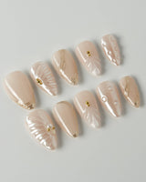 Venus short stiletto nails with pearly nude shine, shells, and gold details