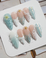 Yasawa Blue medium stiletto nails with pearly blue-white shells and starfish accents