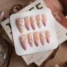 A pink French manicure design accented with white floral dots, exuding elegance and sophistication.