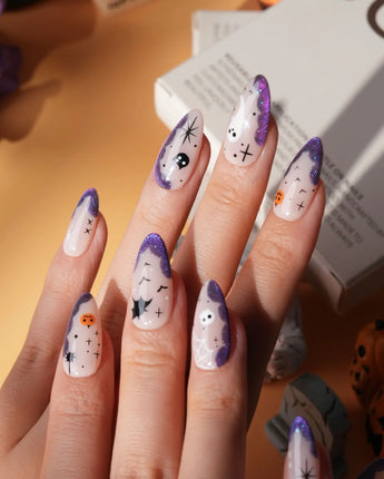 Witching Hour press on nails with a black spider web, bats, ghost, black cat and jack-o'-lanterns on a nude base with purple glitter edges - image 1