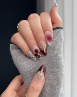 Tip Burgundy Nails with burgundy red French styling, gold cross charm, and delicate flowers