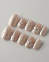Spiral Twist nail close-up with silky nude shimmer, daisy details, and glossy finish