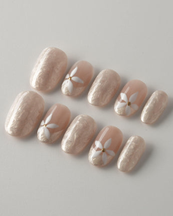 Spiral Twist nail close-up with silky nude shimmer, daisy details, and glossy finish