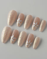 Spiral Twist press-on nails with pearly nude silk effect and delicate daisy nail details